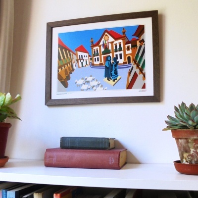Quadro em madeira escura com ilustração colorida de praça com edifício e figuras na parede