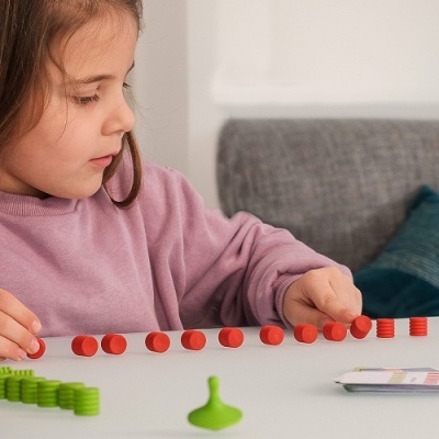 Menina a jogar com peças coloridas numa mesa branca