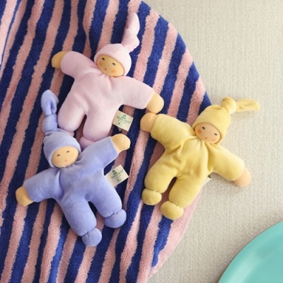 Três bonecos de pano coloridos em rosa, lilás e amarelo sobre tapete às riscas rosa e azul