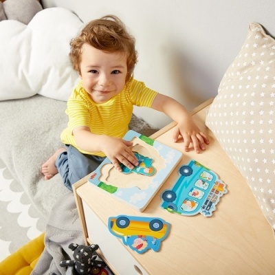 Criança a brincar com puzzle de madeira colorido junto a almofadas