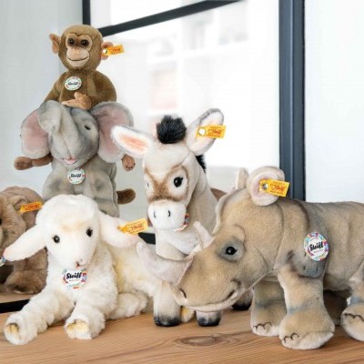 Cinco peluches de animais STEIFF em mesa de madeira com espelho ao fundo