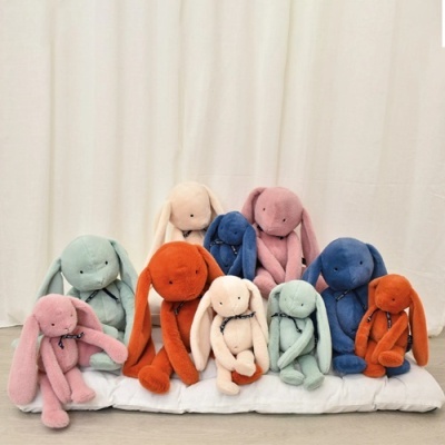 Conjunto de bonecos de pelúcia coelhos coloridos sobre almofada branca