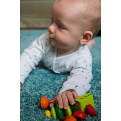 Bebé a brincar com brinquedo em madeira no tapete azul