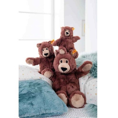 Três ursos de peluche castanhos em cama com almofadas e manta azul