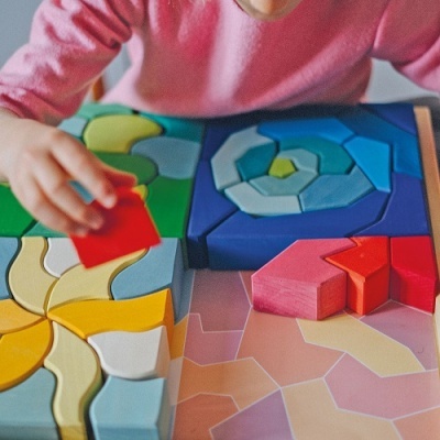 Blocos de construção de madeira coloridos com criança a jogar.