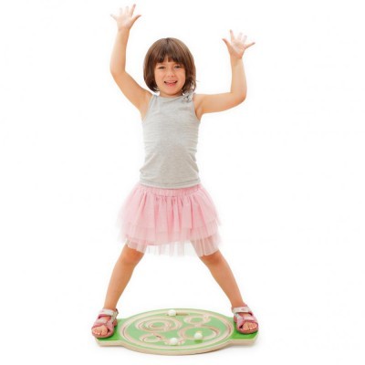 Criança em roupa casual em plataforma de equilíbrio verde de madeira