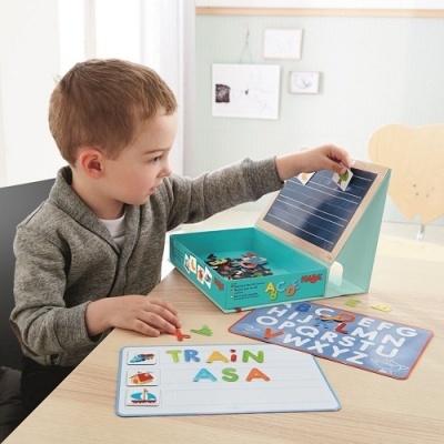 Criança a brincar com letras magnéticas coloridas e tapetes com alfabeto e palavras