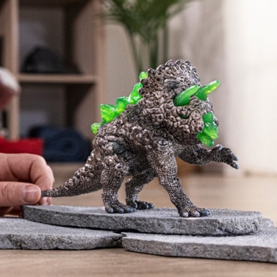 Figura de dinossauro cinzenta com espinhos verdes sobre base cinzenta