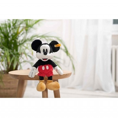 Pelúcia do Mickey Mouse com calções vermelhos sentada numa mesa de madeira