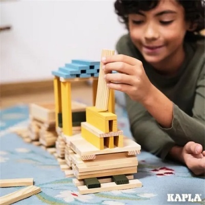 Criança a brincar com blocos de madeira coloridos sobre carpete com padrão