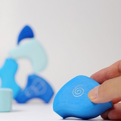 Peças de madeira azuis com padrão de espiral e mão segurando uma peça