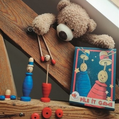 Peças de jogo de madeira coloridas junto a um urso de peluche castanho numa escada de madeira
