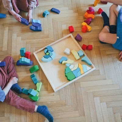 crianças a brincar com brinquedos de madeira coloridos no chão de madeira clara