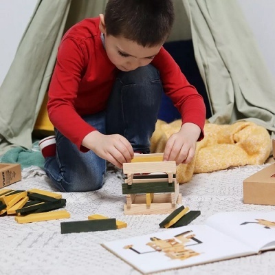 Criança a construir com blocos de madeira coloridos sentada no chão