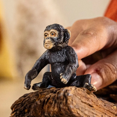 Figura decorativa de macaco sentado sobre madeira com uma mão ao fundo