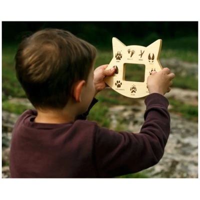 Criança segura régua de madeira com pegadas de animais e texto gravado.