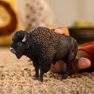 Figura de búfalo de plástico castanho detalhada na mão sobre tecido grosso bege