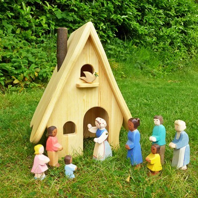 Casa de madeira para pássaros com figuras humanas coloridas em relvado