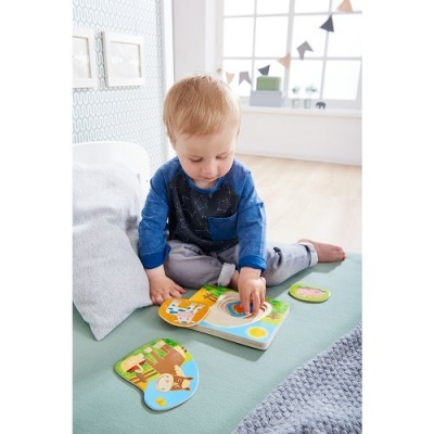Criança a brincar com puzzle de madeira colorido numa cama verde clara