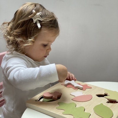 Brinquedo de encaixe em madeira com peças coloridas e criança a brincar