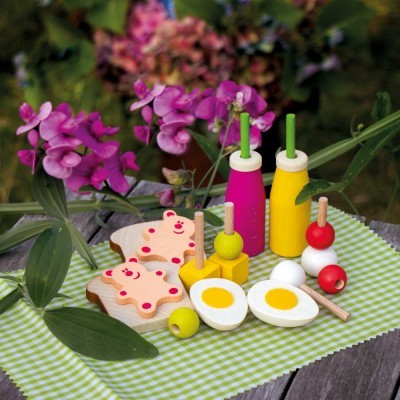 Brinquedos de madeira coloridos representando comida sobre toalha verde e branca em mesa de madeira