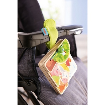 Livro de madeira para bebés com imagens de animais coloridos pendurado numa cadeira de criança.