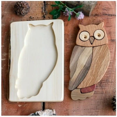 Quebra-cabeça de madeira em forma de coruja e molde sobre mesa de madeira