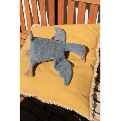 Brinquedo de pelúcia cinzento em forma de pato sobre almofada amarela numa cadeira de madeira