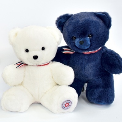 Dois ursos de peluche, um branco e outro azul escuro, com laços às riscas ao pescoço