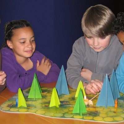 Crianças jogando jogo de tabuleiro com peças triangulares coloridas