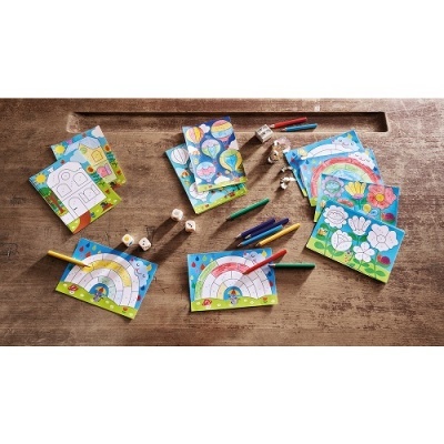 Jogos de tabuleiro e cartas coloridos com lápis de cor, dados e peças pequenas numa mesa