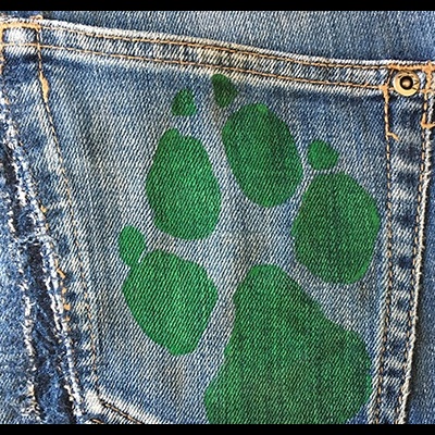 Calças de ganga azuis com impressão verde de pata no bolso traseiro