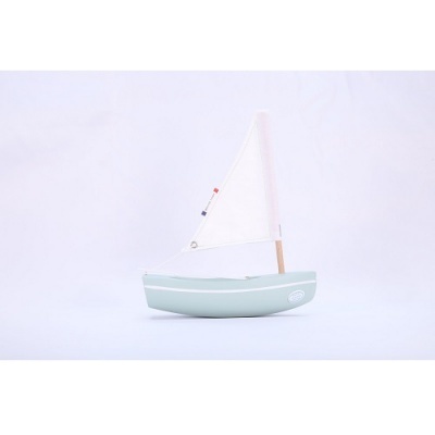 Barco de vela decorativo verde claro com vela branca em fundo branco.