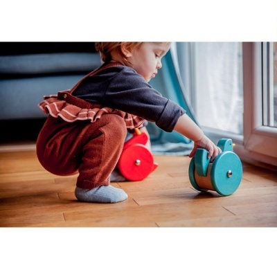 Criança a brincar com brinquedos de madeira vermelho e azul junto a porta de vidro