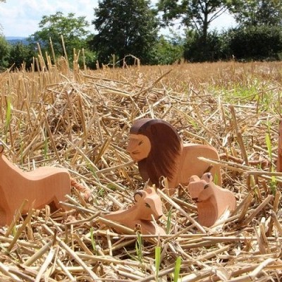 Figuras de madeira de animais selvagens numa campo com palha