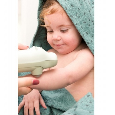 Criança enrolada em toalha verde com pontos e mão a aplicar creme