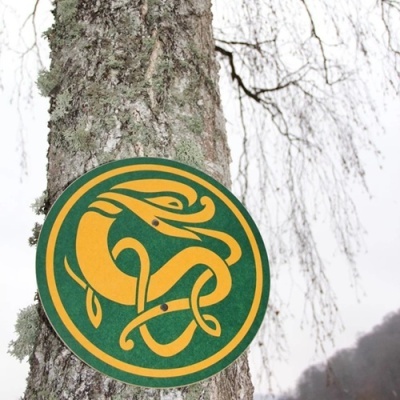 Placa redonda verde com desenho amarelo num tronco de árvore