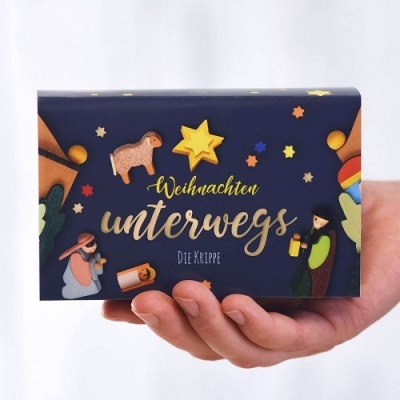 Caixa azul escura com ilustrações de figuras de presépio e texto em alemão