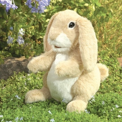 Pelúcia de coelho bege e branco sobre relva com flores