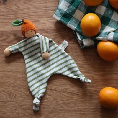 Boneco de peluche com corpo riscado verde e branco e cabeça laranja em forma de fruta