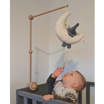 Bebé a olhar para um móvel de berço em madeira com uma lua branca felpuda e um coelho cinzento de tecido