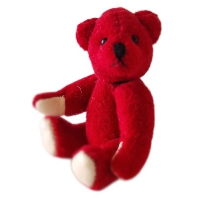 Urso de peluche vermelho sentado em fundo branco