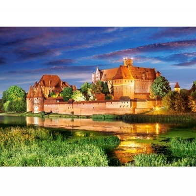 Castelo histórico em tijolo vermelho junto a rio e relvado verde ao entardecer