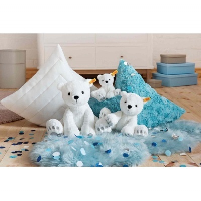 Peluches de ursos polares brancos com almofadas e tapete azul felpudo num ambiente com piso de madeira clara