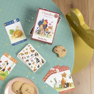 Jogo de cartas 7 familles com imagens de animais sobre mesa azul e cadeira amarela em forma de urso