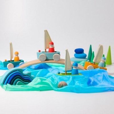 Brinquedo de madeira com barquinhos, figuras e acessórios sobre tecido azul