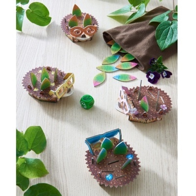 Jogo de tabuleiro com peças de ouriços em papel e papelão com acessórios, dados e saco marrom sobre mesa clara.