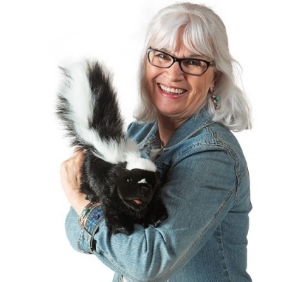 Mulher idosa a segurar pelúcia de gambá preto e branco