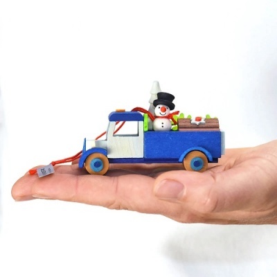 Carrinha decorativa azul e branca com boneco de neve a transportar presentes e troncos na mão