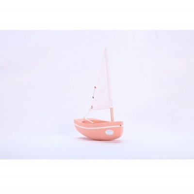 Barco de brinquedo cor de salmão com vela branca